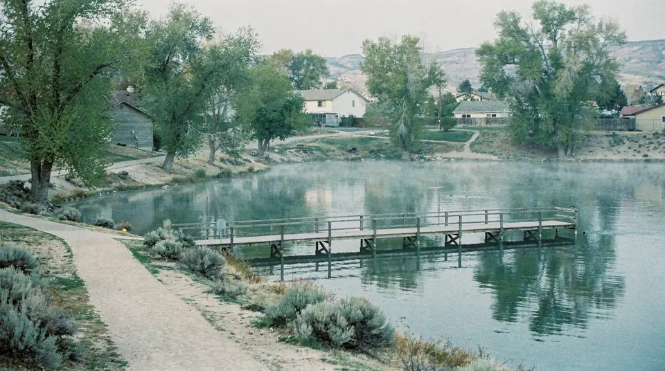 A small park fishing pond with a wooden pier and cottonwood trees