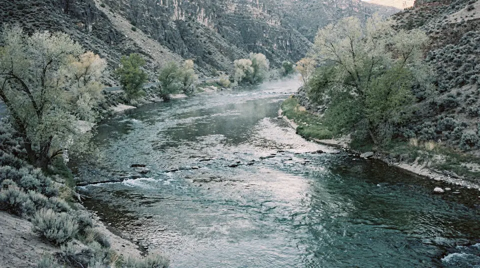 A clear river winding through a sagebrush canyon in early light