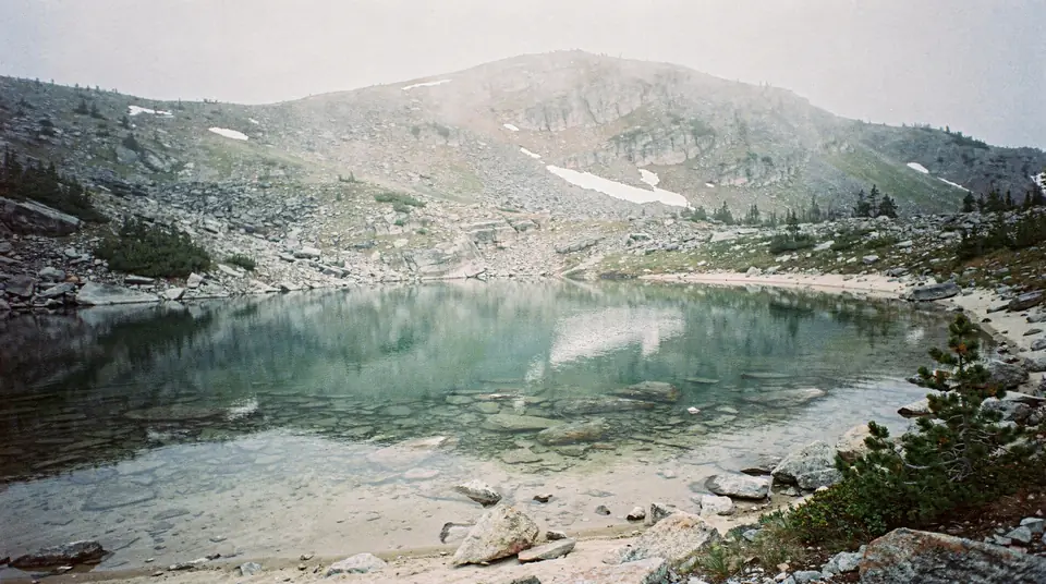 A small high alpine lake among rocky slopes and scattered spruce
